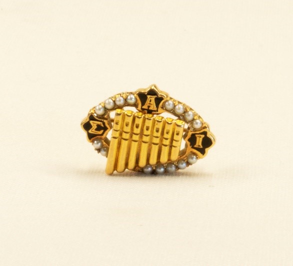 A lapel pin in the shape of a pan flute from the Sigma Alpha Iota music fraternity, (ca. 1930).