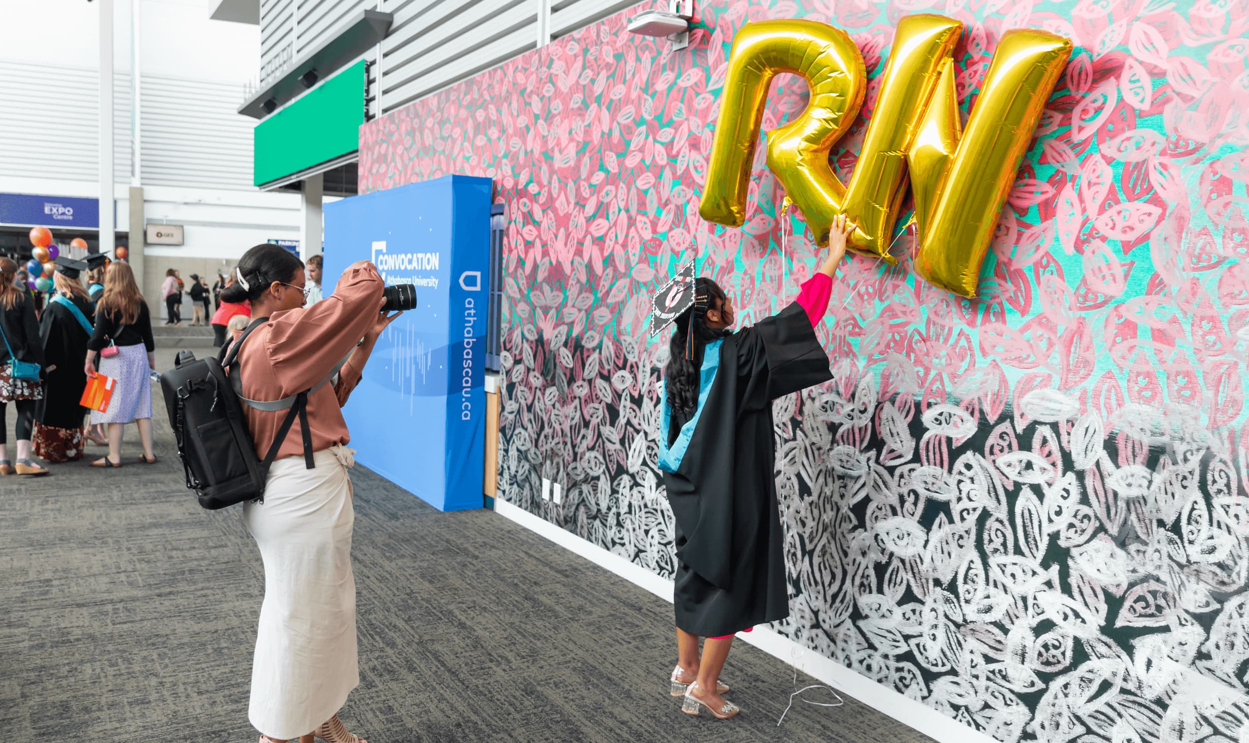 photo of AU graduate holding two large letter ballons spelling out RN for registered nurse