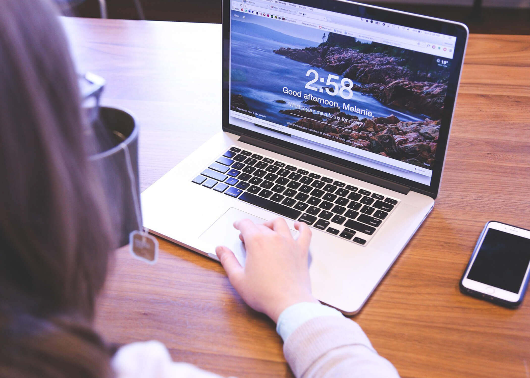 Woman working on computer while drinking coffee